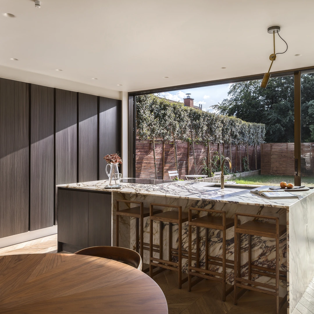 Calacatta marble waterfall island with walnut stools, designed and fitted by Urban Kitchens & Interiors
